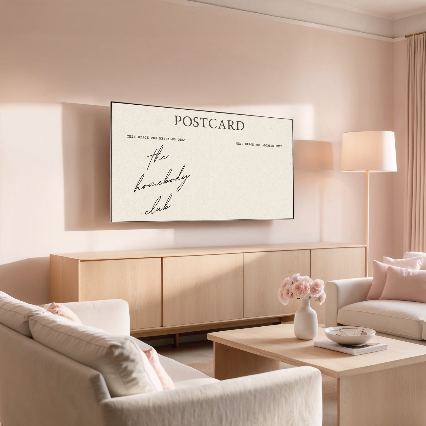 Modern living room with a 'Postcard' print on the wall, featuring the text 'the homebody club'.