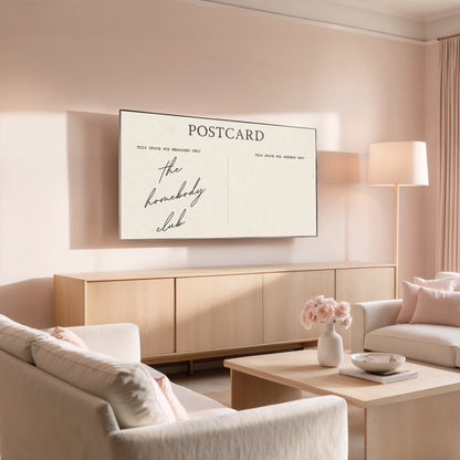 Modern living room with a 'Postcard' print on the wall, featuring the text 'the homebody club'.