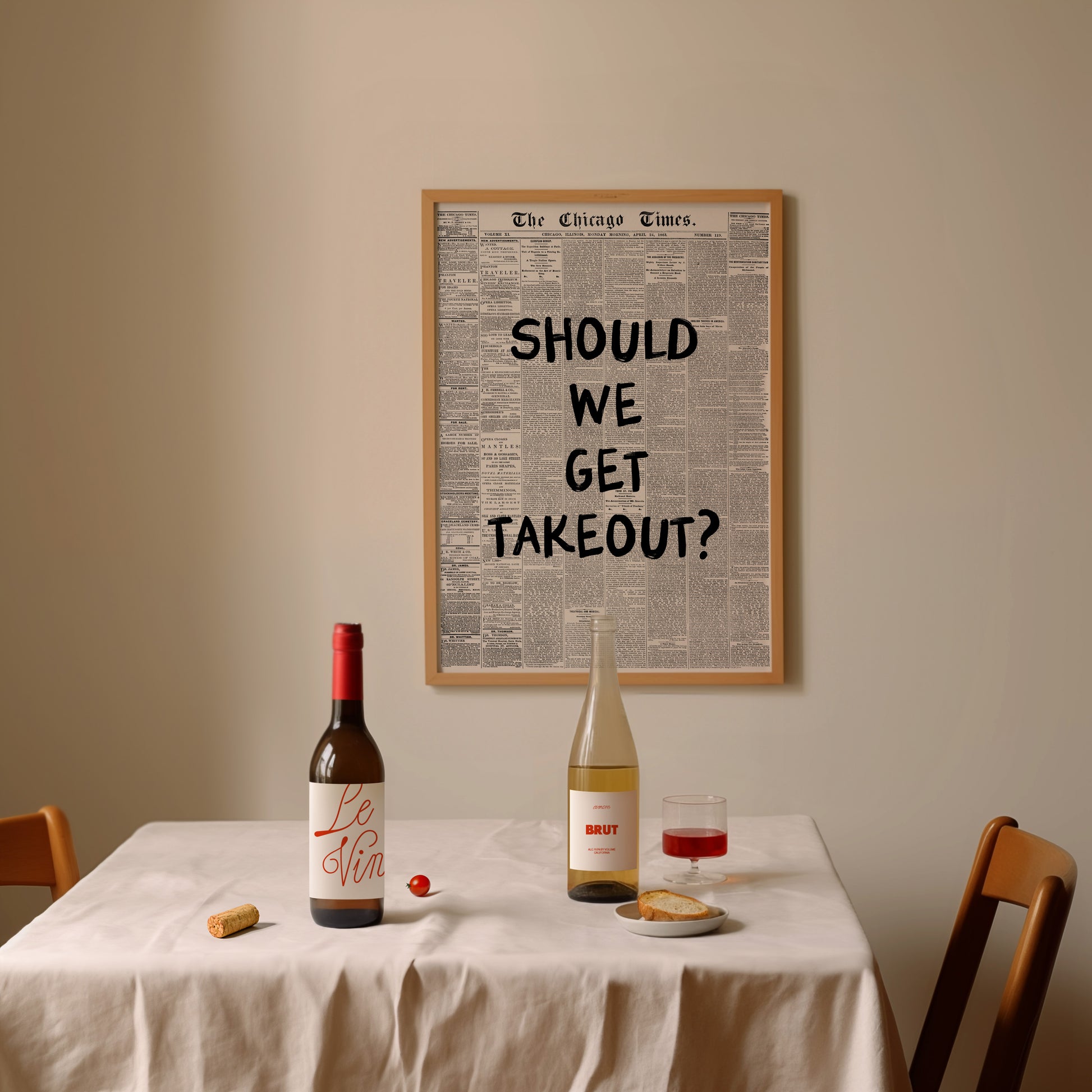 Dining table with wine bottles, a glass, and a framed newspaper question on the wall.