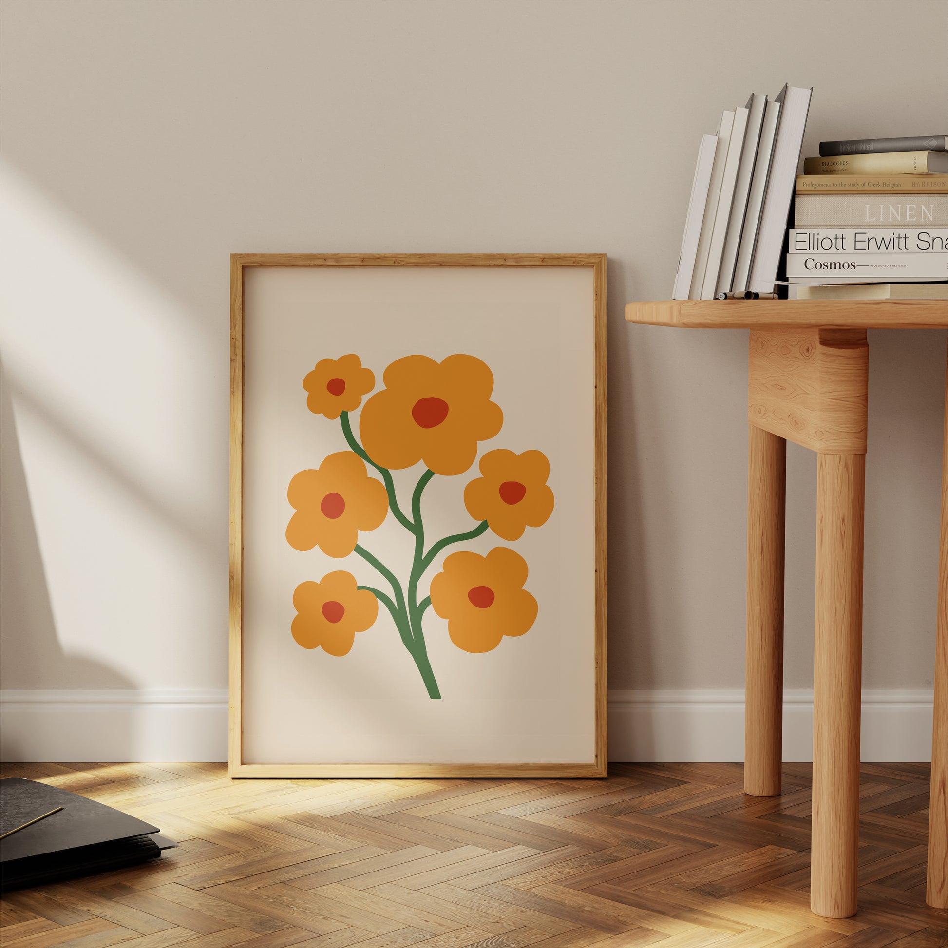 Framed floral artwork on a wall next to a wooden side table with books.